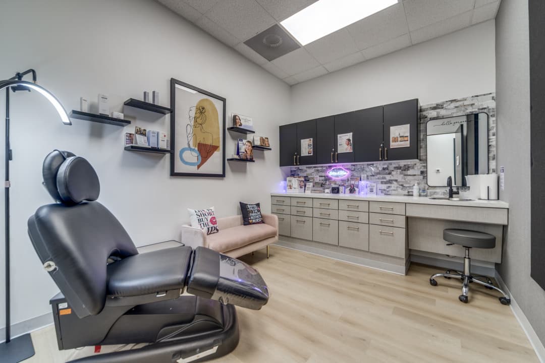 Treatment room with exam chair, product shelves, and vanity area