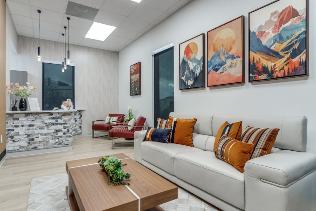 Waiting room with sofa, colorful pillows, and framed wall art