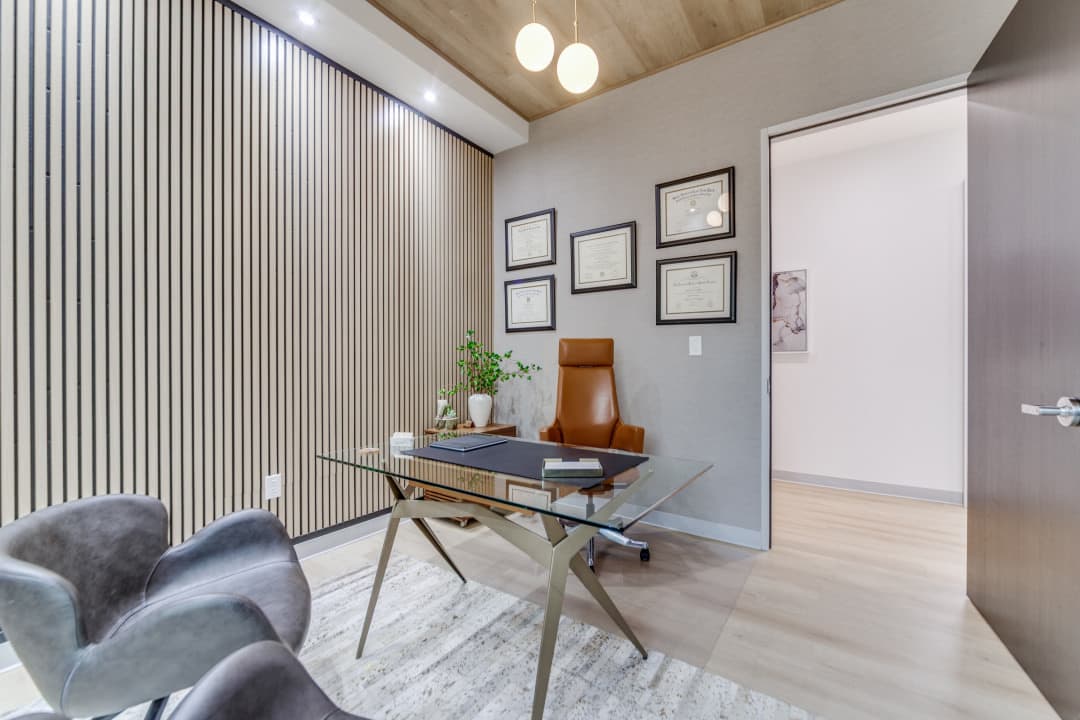 Consultation office with glass desk and framed certificates
