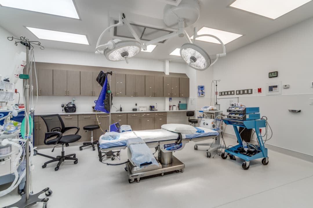 Operating room with surgical table, equipment carts, and overhead lighting