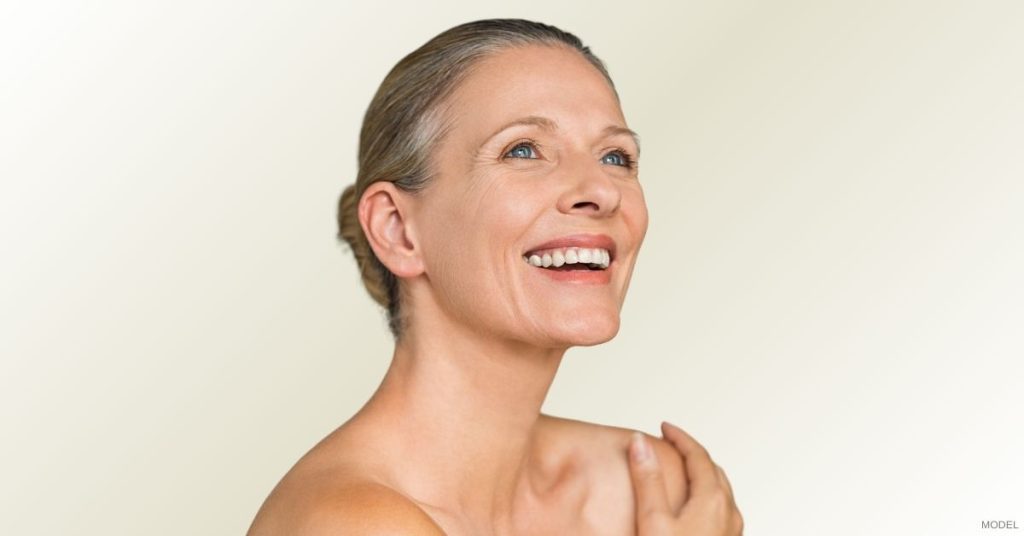 Woman with her hair in a bun smiling happily. (Model)